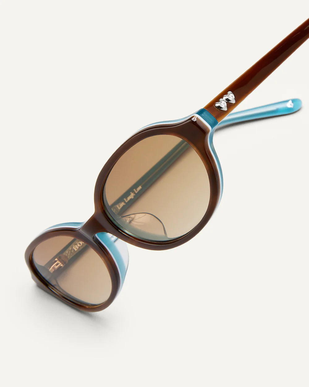 Angled view of Bonnie Clyde Baby Sunglasses Layered Teal Demi Brown Gradient