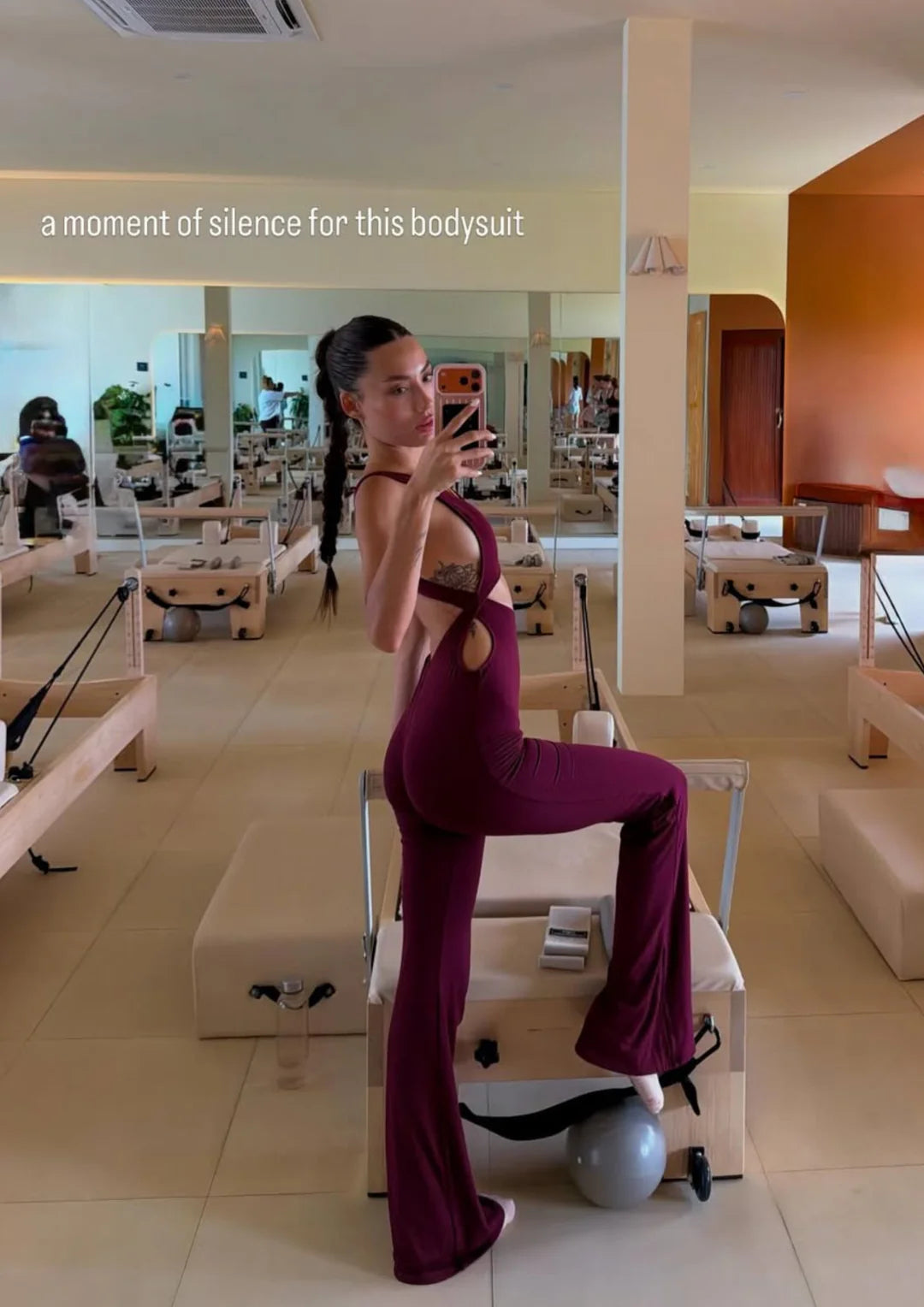 Model wearing WearRame Leda Dynamic Full Body Flare Onesie in Burgundy indoors