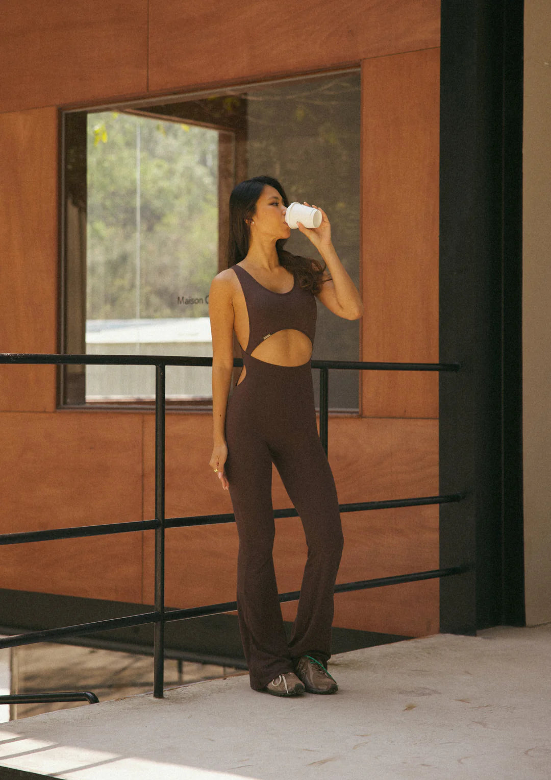 Model wearing WearRame Leda Dynamic Full Body Flare Onesie in Espresso indoors