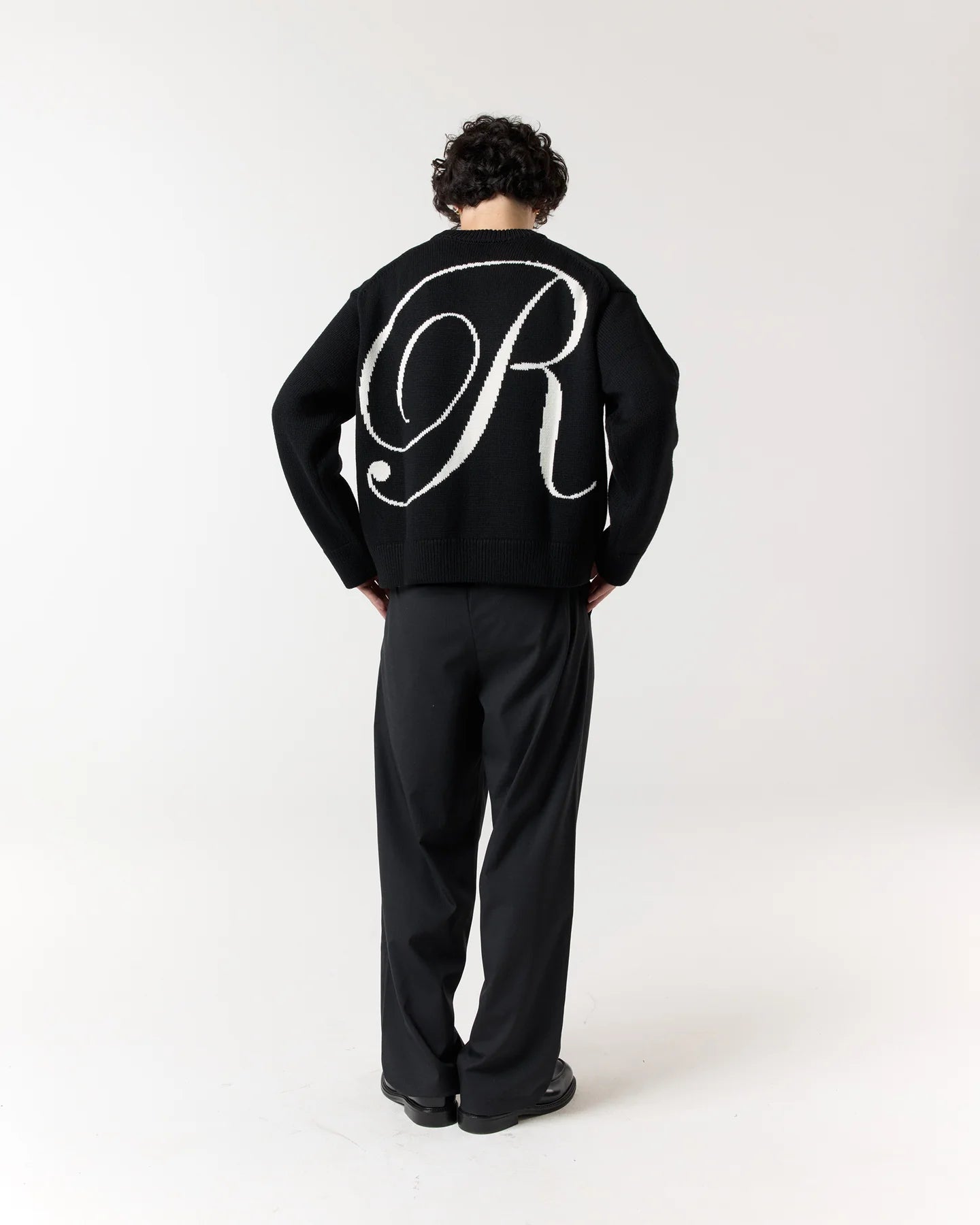 Back view of model wearing RONNING R Knit Sweater in Black