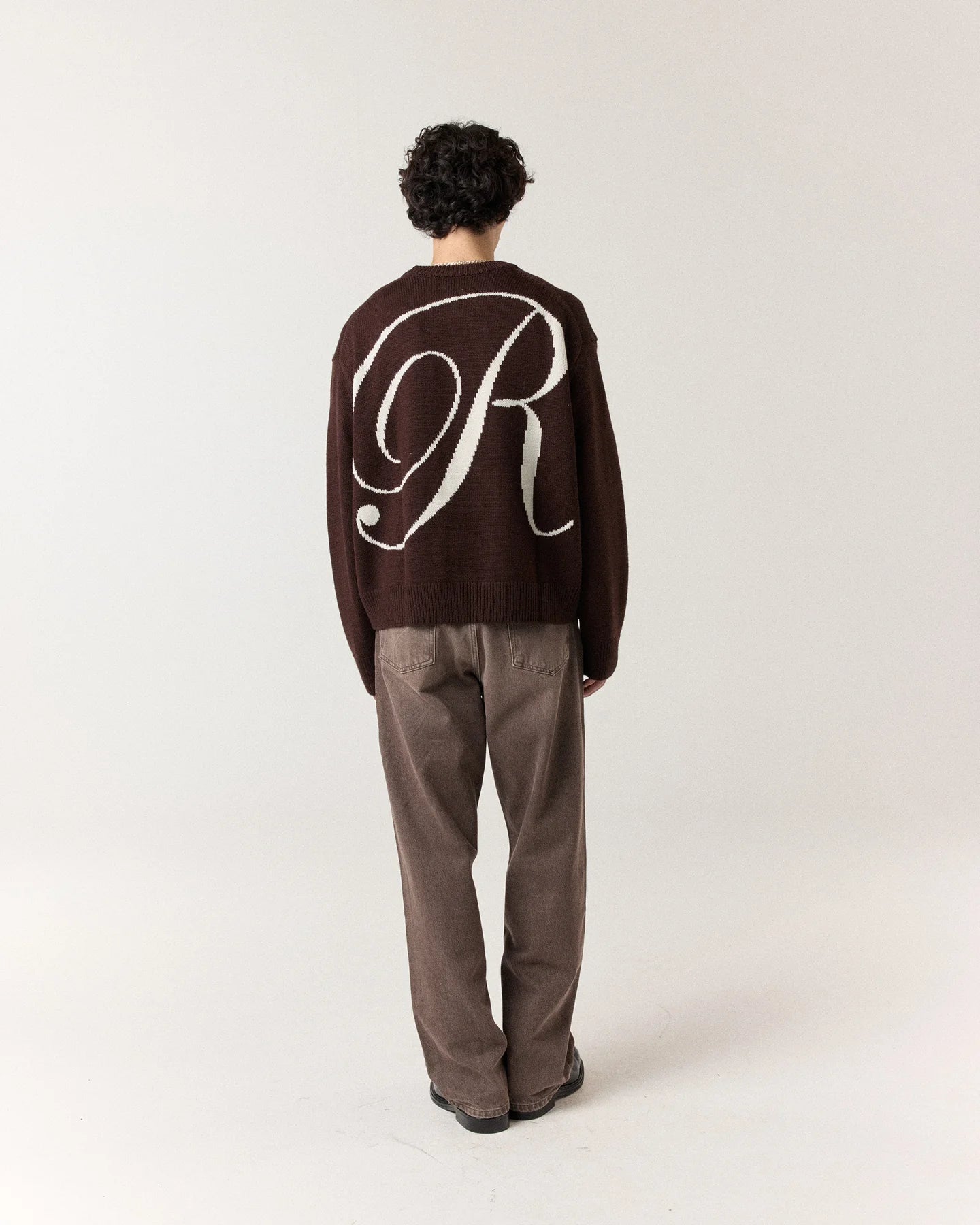 Back view of model wearing RONNING R Knit Sweater in Mocha Brown